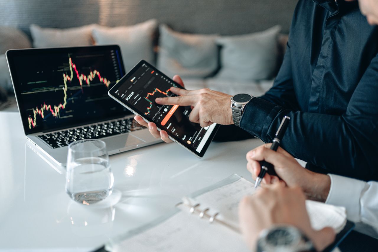 who-we-are Professionals analyzing financial data on a tablet and laptop in an office setting.